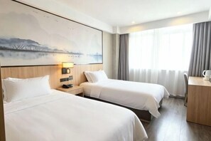A hotel room with two beds, a desk, a chair, a lamp, and a painting on the wall. - Qingmu Hotel (Nanjing Xinzhuang Metro Station) (Nanjing)