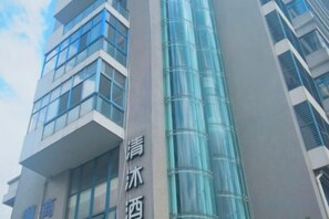 A modern building with a glass facade and a sign with Chinese characters. - Qingmu Hotel (Nanjing Xinzhuang Metro Station) (Nanjing)