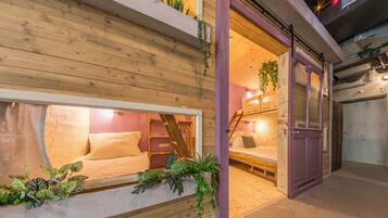A cozy interior with a wooden wall, a window with a bed, and a purple door.