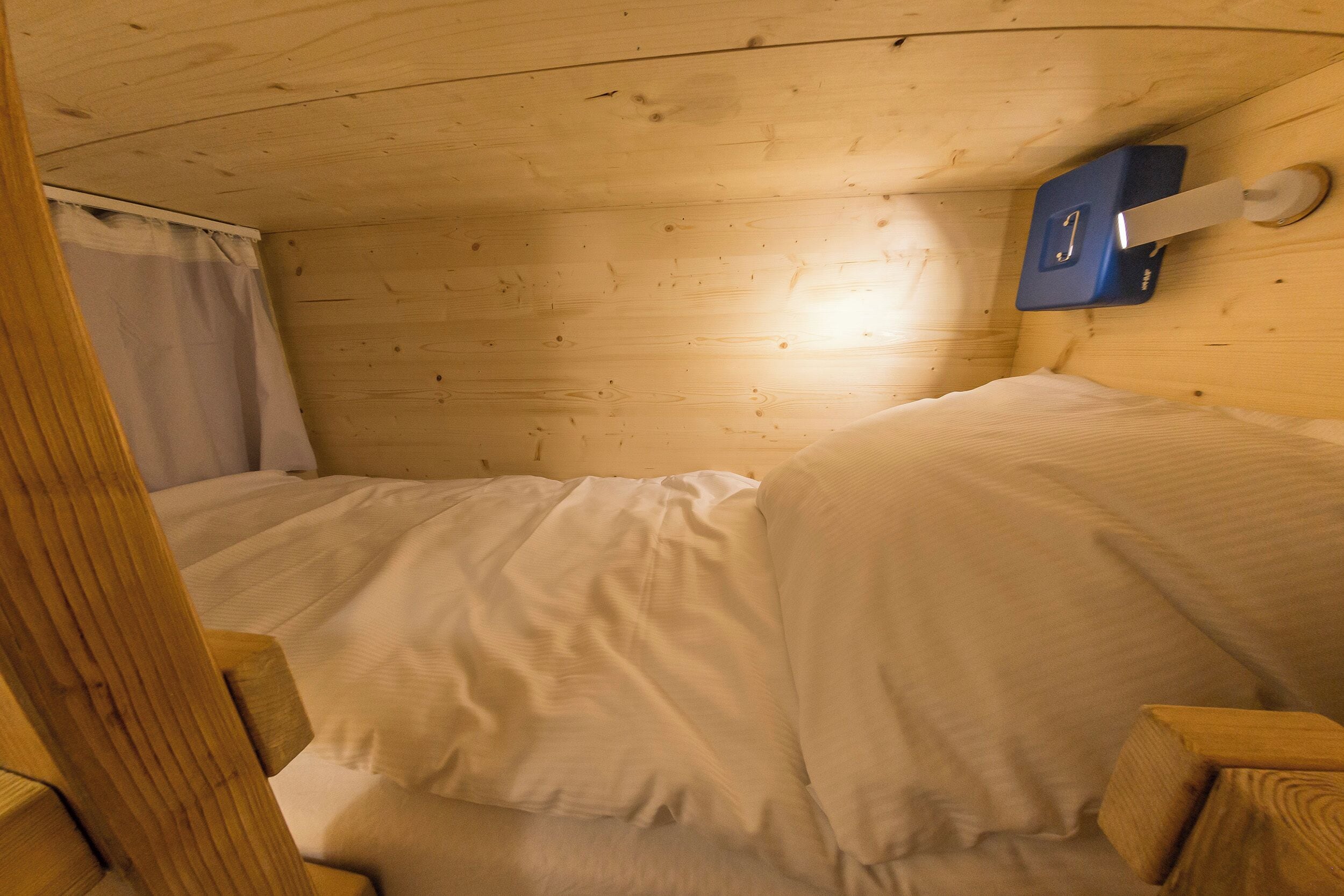 Una habitación tipo cabaña de madera con una cama, una mesita y un calentador fijado a la pared.