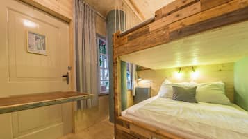 Un lit superposé en bois, avec une tête de lit, une table de chevet et une fenêtre avec des rideaux.