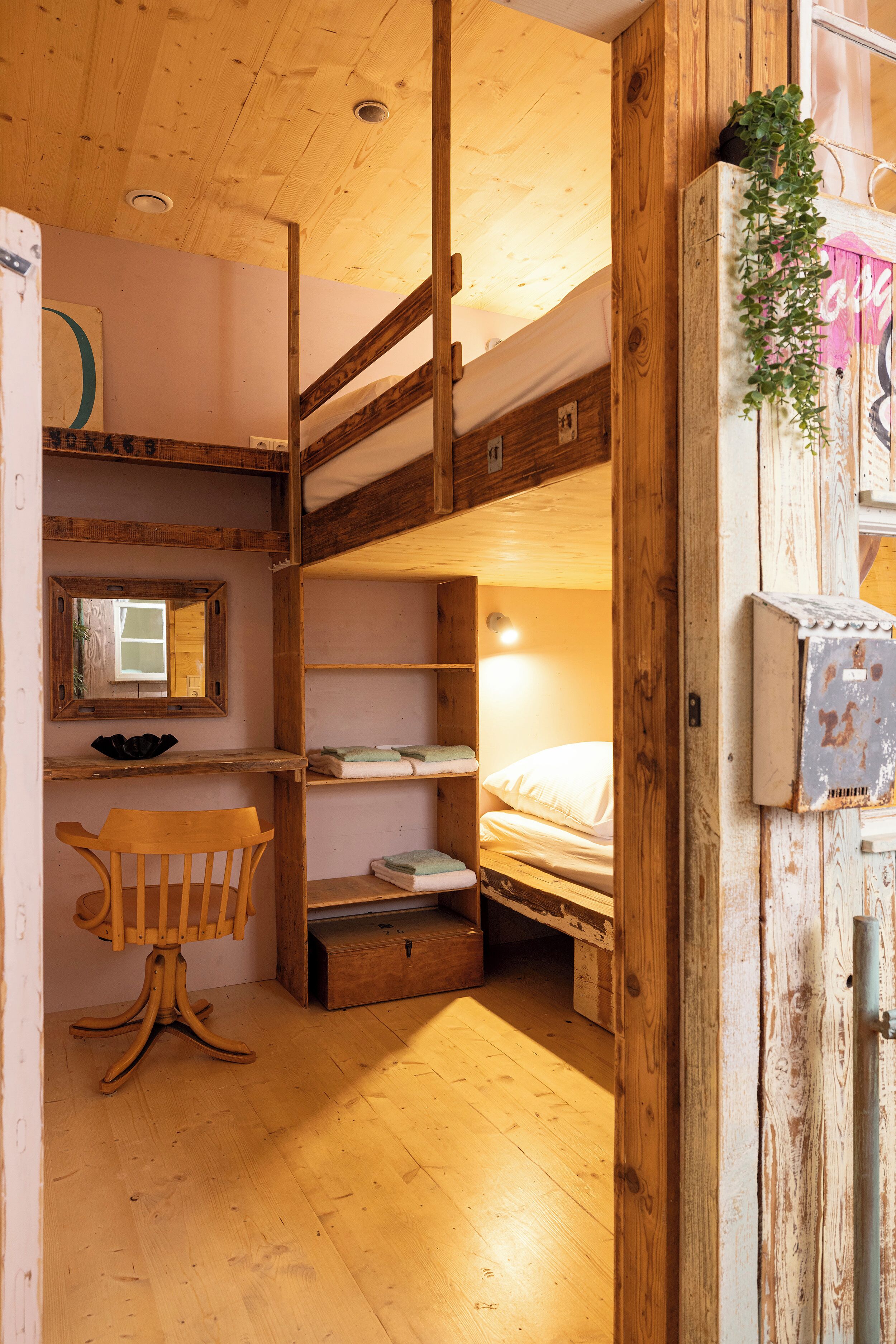A compact room with a bunk bed, a desk with a chair, and a small window.