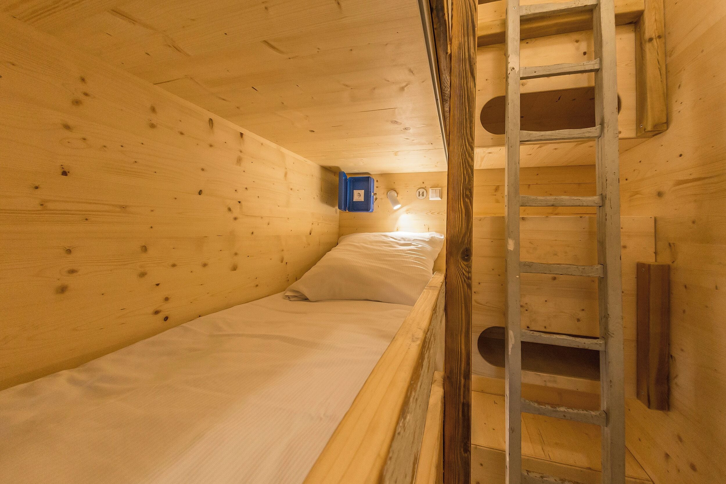 Ein Zimmer einer Holzhütte mit einem Etagenbett, einer Halterung und einer kleinen, blauen Aufbewahrungsbox.