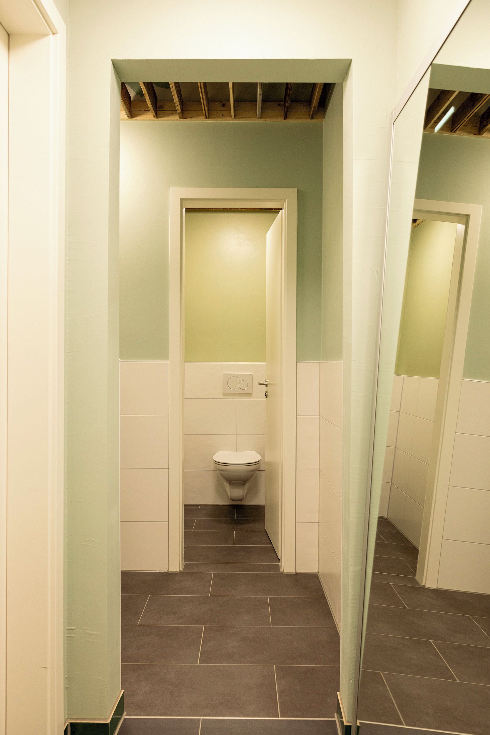 Un bany estret amb un vàter, un mirall i una porta.