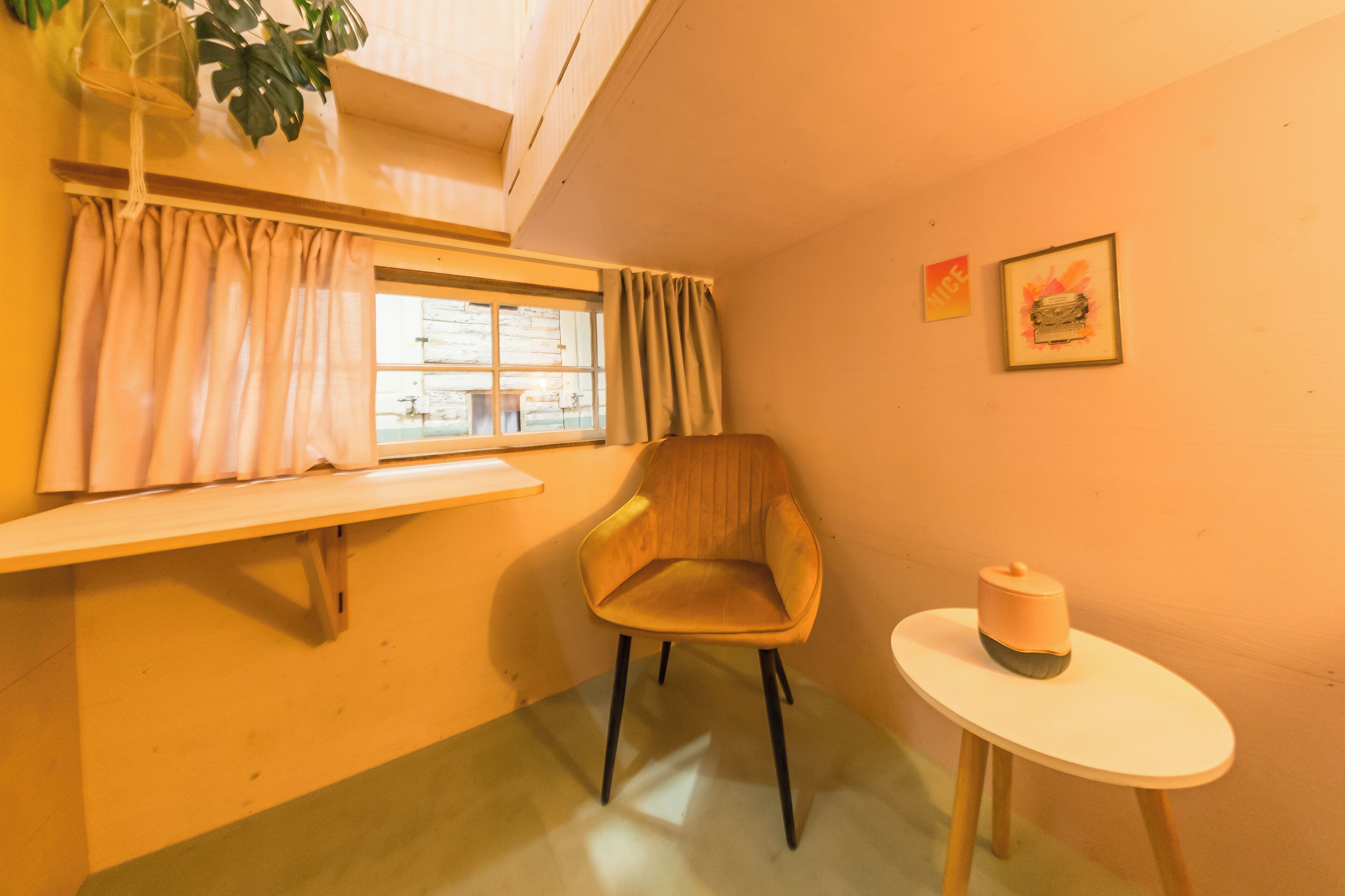 A room with a window, a chair, a small table, and a plant.