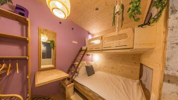 A compact room with a bunk bed, a wooden desk, a chair, and a hanging light fixture.