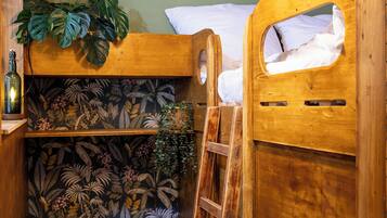 A bunk bed with a wooden headboard, a ladder, a small wooden desk, and a chair.