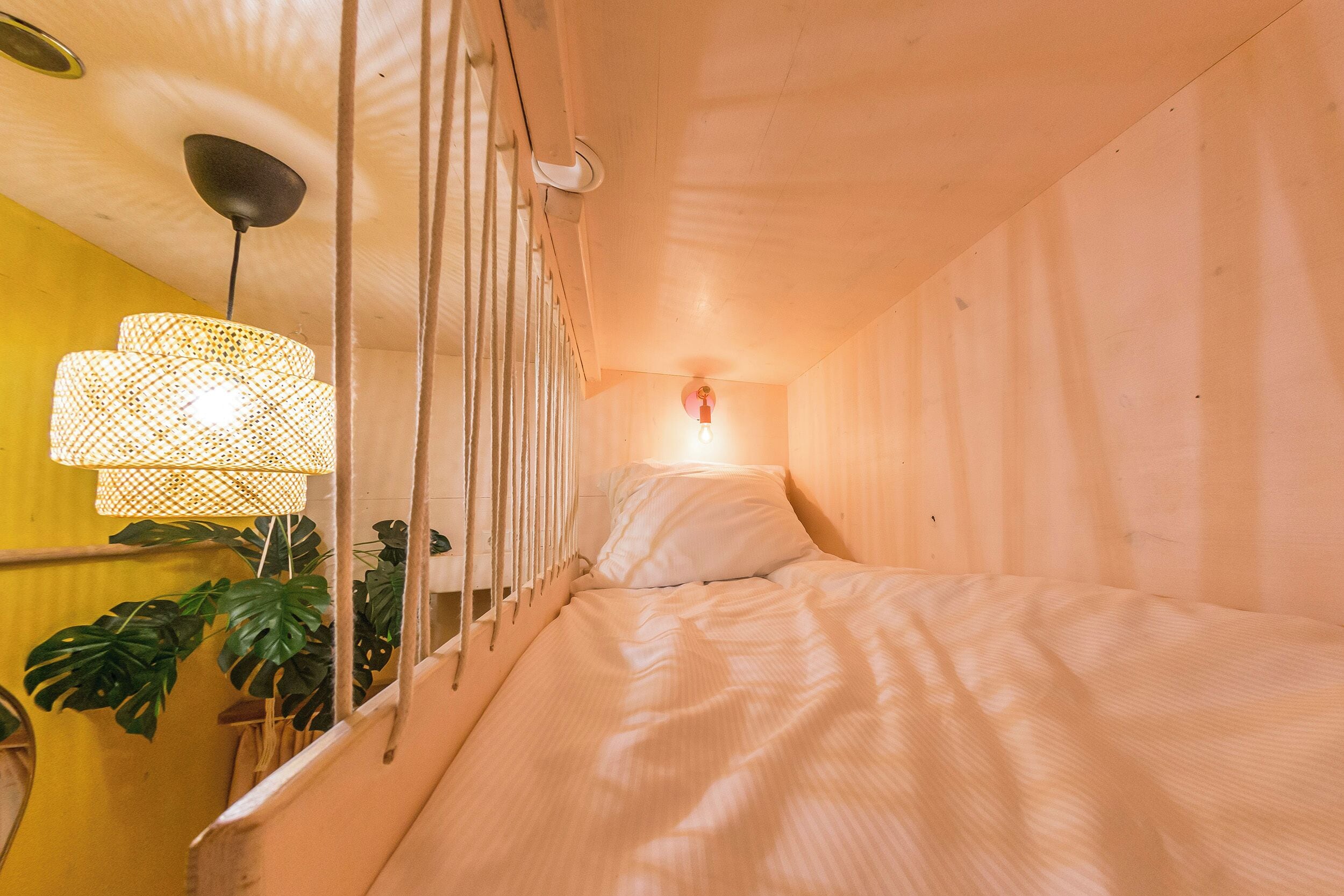 A room with a bed, a hanging light fixture, and a wall-mounted light.