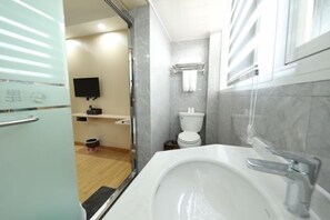 A bathroom with a white sink, a toilet, a shower, and a mirror. - Kunxin Hostel (Shanghai)