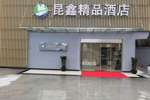 A hotel entrance with a red carpet, a logo, and a signboard. - Kunxin Hostel (Shanghai)