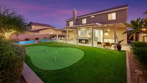 Ein modernes Haus mit gepflegtem Rasen, einem Pool und einer überdachten Terrasse.