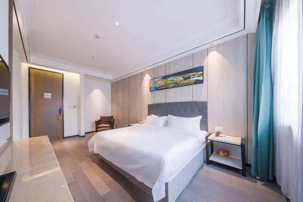 A hotel room with a bed, bedside table, and a painting on the wall.