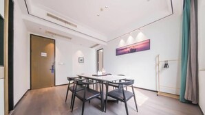 A hotel room with a dining table, chairs, a bed, a bedside table, a nightstand, a window, and a door. - Homeinn Fairyland Hotel (Linhai Yintaicheng) (Linhai)