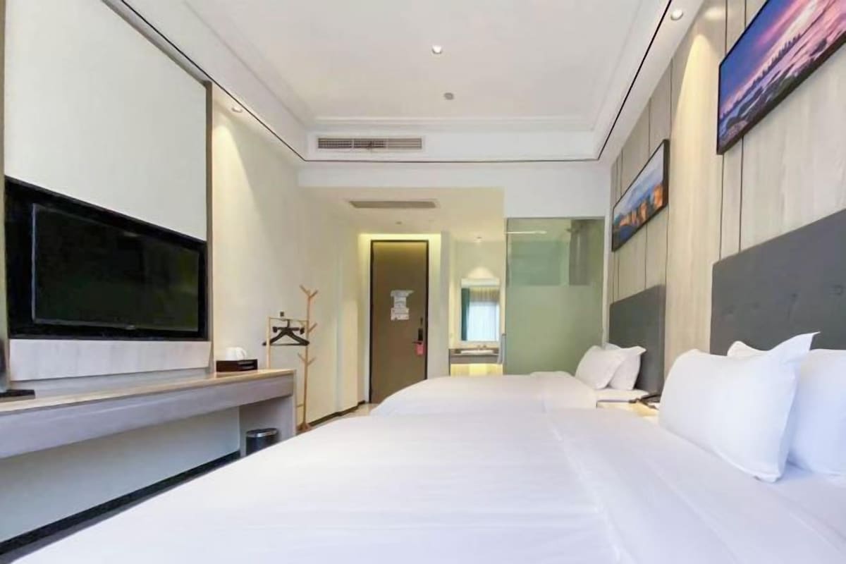 A hotel room with a bed, a TV, a desk, and a mirror.