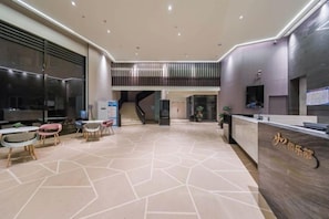 A hotel lobby with a reception desk, seating area, and a staircase leading to an upper level. - Homeinn Fairyland Hotel (Linhai Yintaicheng) (Linhai)