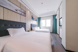 Una habitación de hotel con dos camas, un ventanal grande y un cuadro en la pared.