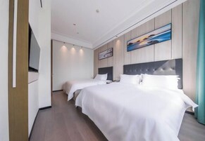 Una habitación de hotel con dos camas, un televisor de pantalla plana, paneles de madera y obras de arte.