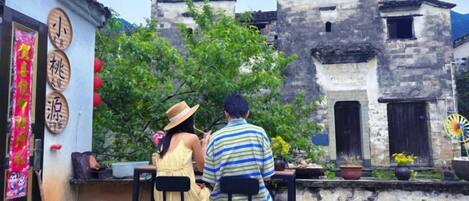 A couple seated at an outdoor table with traditional Chinese decorations, overlooking old-style buildings.