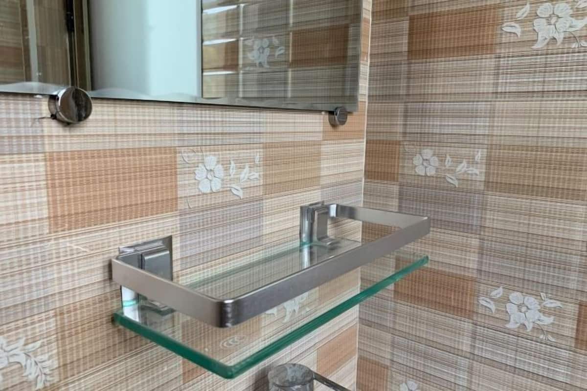 A bathroom with a glass shelf, a mirror, and patterned tiles.