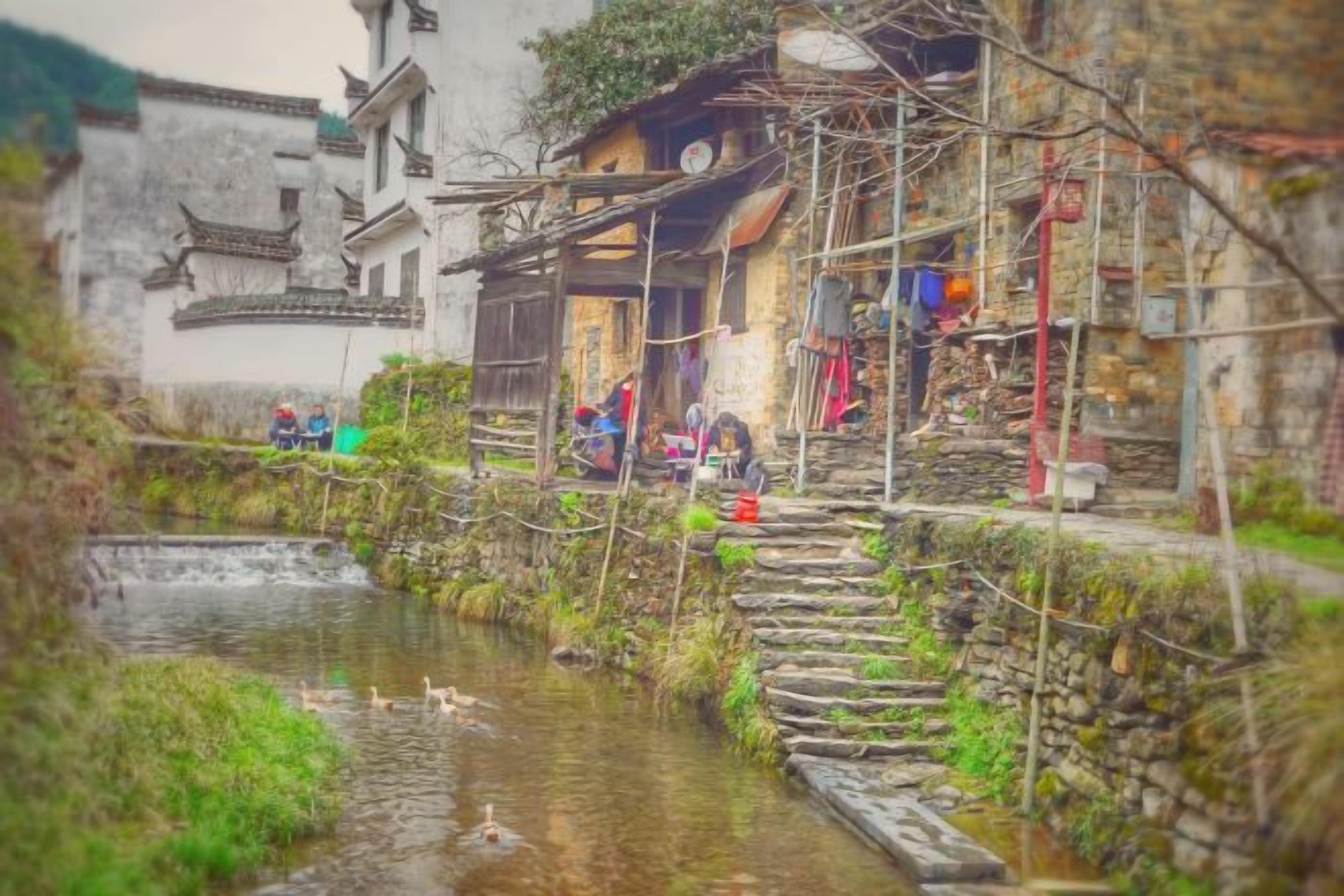 A traditional building with a water channel in front, wooden steps, and a rustic exterior.
