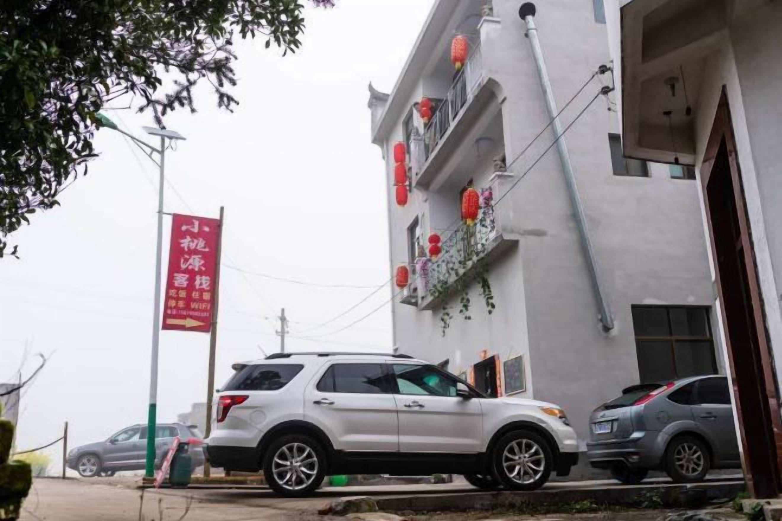 A building with a white facade, red signage, and a parked white SUV.