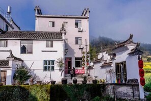 A traditional building with a red door, a balcony, and a small garden area. - Xiaotaoyuan Inn (Wuyuan)