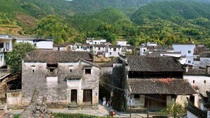 Un village traditionnel aux maisons en pierre, situé au pied de montagnes.