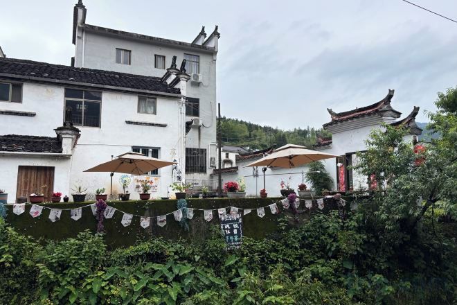 A traditional building with a white facade, multiple windows, and a balcony with umbrellas.