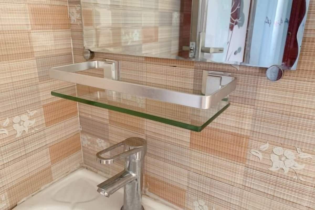 A bathroom with a glass shelf, a chrome faucet, and patterned tiles.