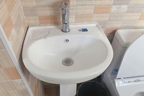 A bathroom with a white sink, a toilet, and a trash bin. - Xiaotaoyuan Inn (Wuyuan)