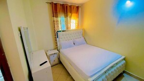 A bedroom with a single bed, a nightstand, a wardrobe, and a window with curtains. - Bondeni Mombasa city (Mombasa)