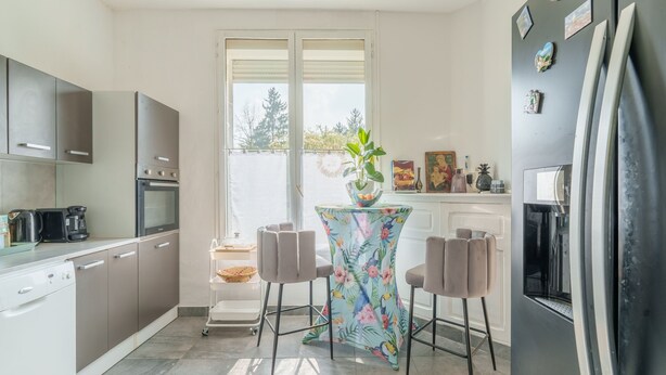 Une cuisine moderne avec un coin repas, un réfrigérateur et une fenêtre donnant sur un beau paysage.