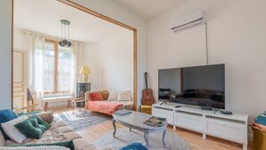 Un salon avec un canapé, une table basse, un téléviseur et une guitare.