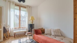 Une pièce confortable avec un canapé, une petite table, une lampe et une fenêtre avec des rideaux.