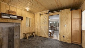 A wooden interior with a fireplace, bench, and sliding door leading to a dining area. - Emily Channel Cabin on the water with ATV trail access from your doorstep! (Emily)