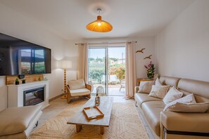 Una sala de estar moderna con chimenea, sofá, mesa de centro y televisor.