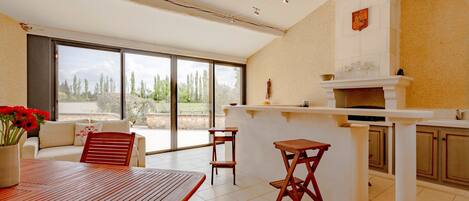 A spacious living area with a large window, a wooden table, and a bar area.