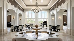 Eine großzügige Lobby mit einer prächtigen Kristallleuchter, einem Brunnen und einem Flügel.