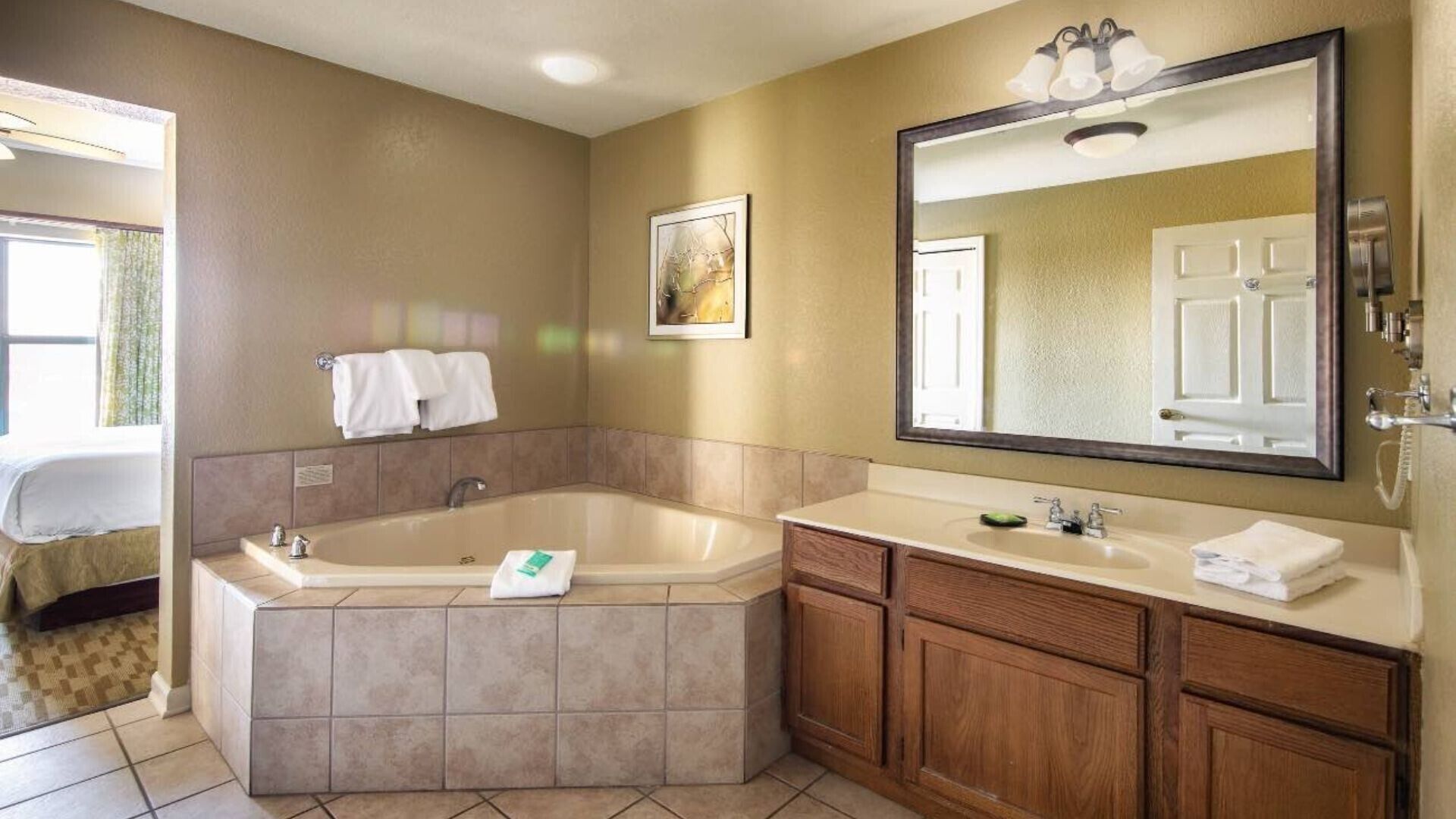 A bathroom with a large bathtub, a vanity with a mirror, and a shower area.