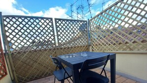 Eine Terrasse mit Tisch und Stühlen, einem Holzzaun und einem gefliesten Boden.