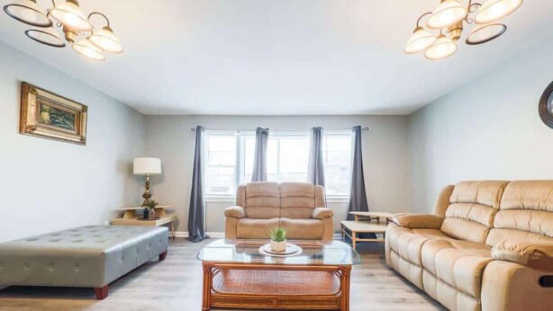 Een woonkamer met een bank, een lange bank, een salontafel en een lamp.