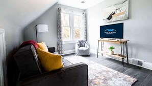 Moderni olohuone, jossa on sohva, säkkituoli, televisio ja ikkuna, jossa on verhot.