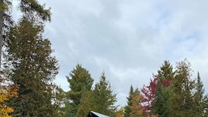 A rustic cabin with a porch, a grill, and a small deck.