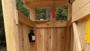 A wooden structure with a black bucket labeled "Pro X" and a hose.