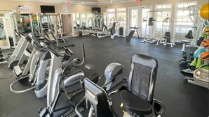 Et fitnesscenter med forskellige træningsmaskiner, spejle og vinduer.