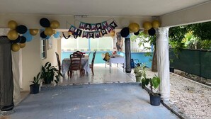 A covered patio area with a birthday banner, balloons, and a table set up for a celebration. - 6-bedroom studio in welcoming Ocho Rios with WiFi, AC Escape to Tranquility (Ocho Rios)