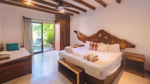 Um quarto amplo com uma cama grande, cabeceira de madeira e porta de vidro que se abre para uma varanda.