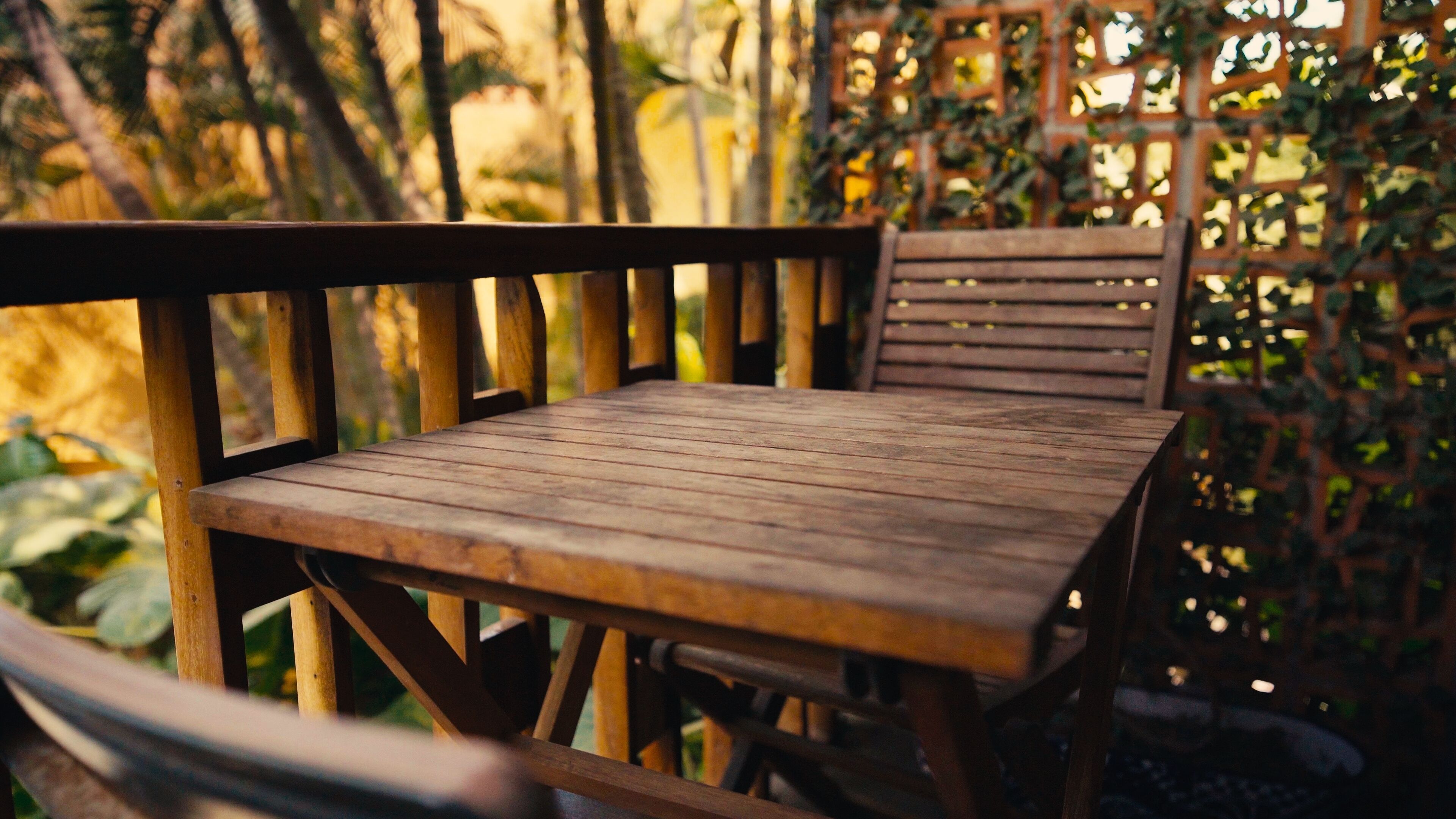 Une terrasse en bois avec une table et des chaises, entourée de verdure.