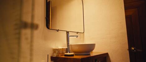 Un baño con lavamanos blanco, un espejo y un armario de madera.
