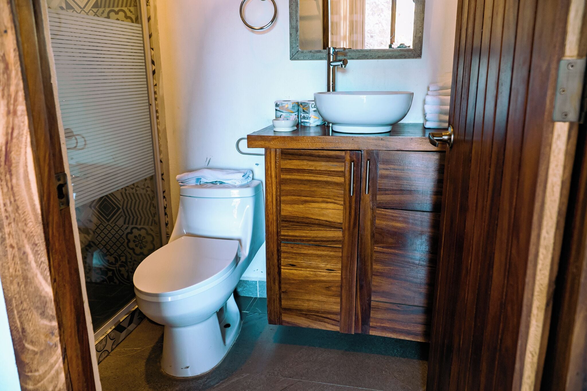 Un baño con tocador de madera, un lavamanos blanco y un inodoro.